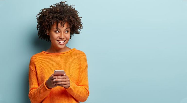 Woman in orange sweater on her phone
