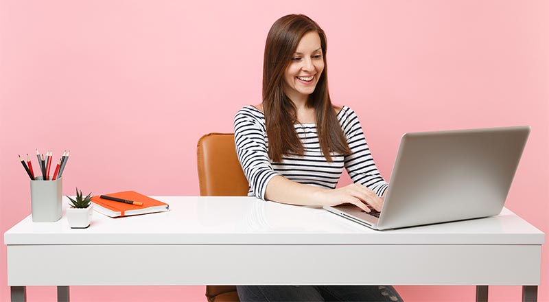Woman sitting at a white desk with her laptop
