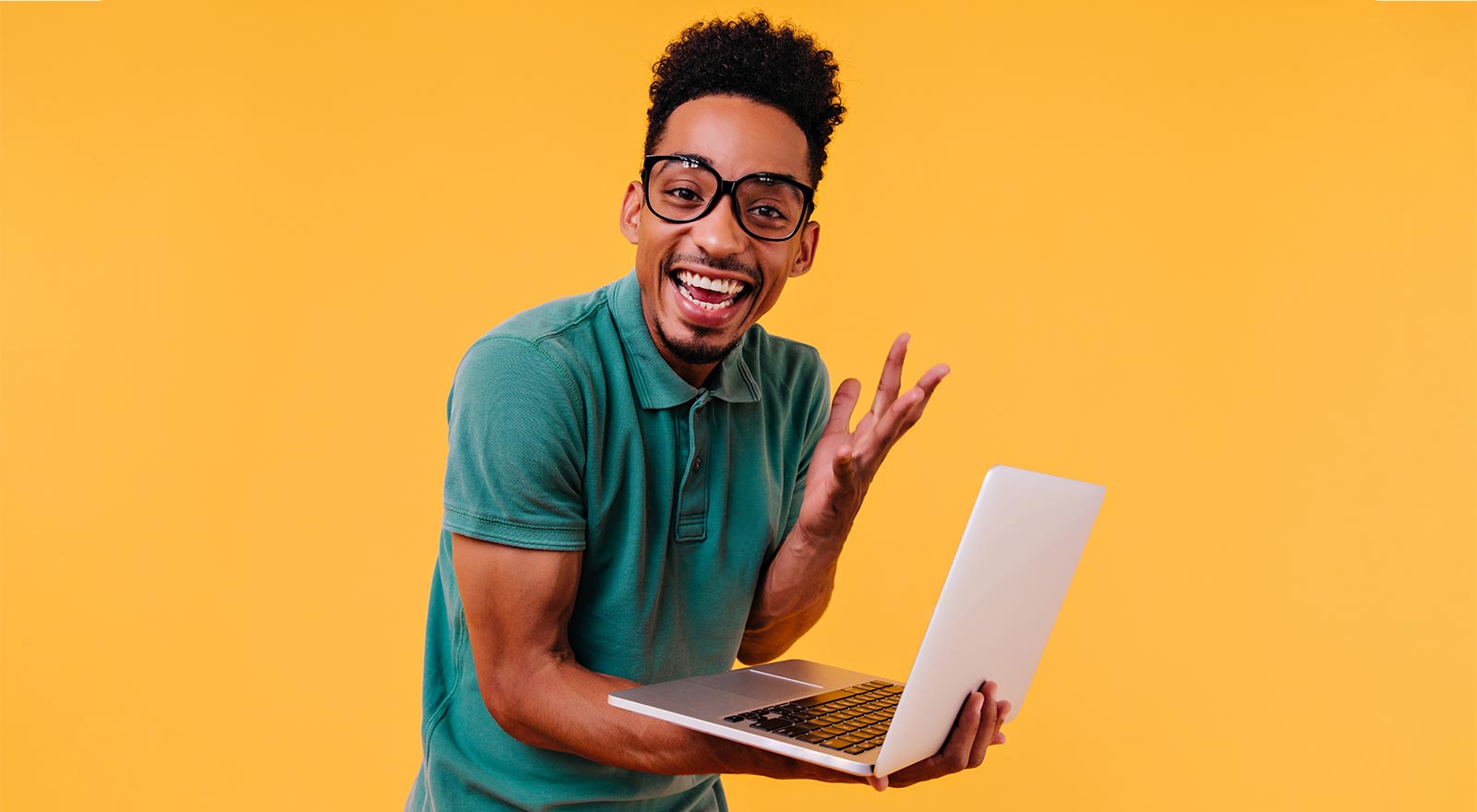A happy man with glasses, holding a computer