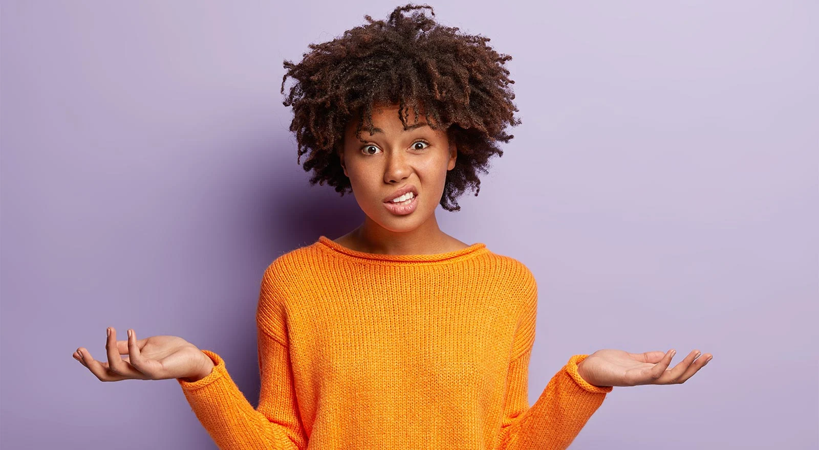 A woman looking confused and shrugging her shoulders.