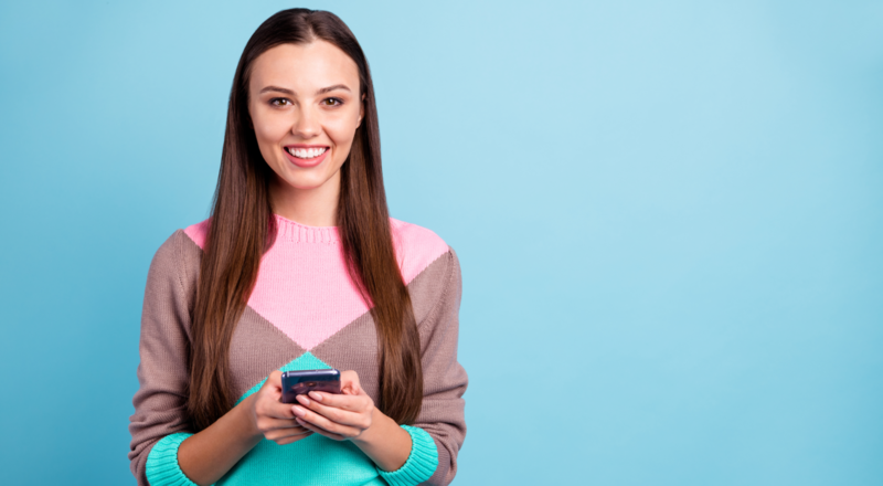 smiling brunette woman uses phone to scroll social media