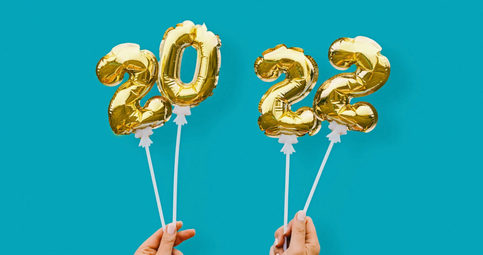 New year number 2022 in golden balloons held by hands