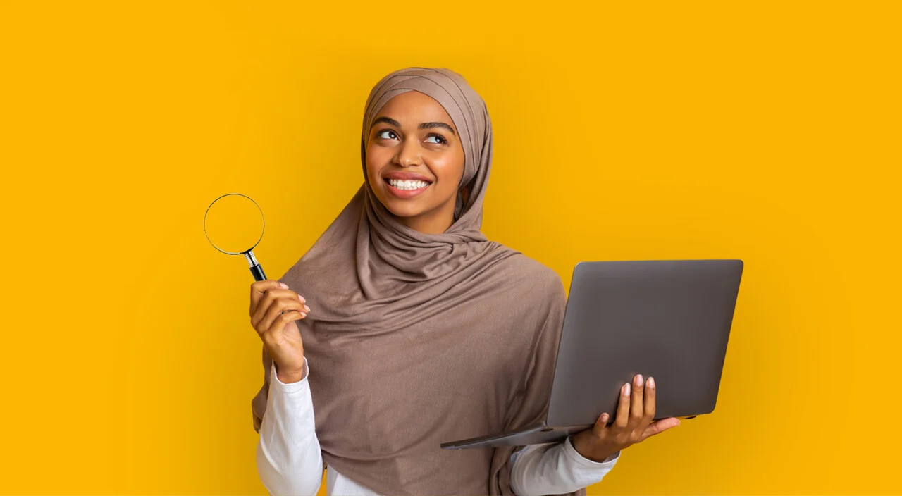 A woman holding a magnifying glass and laptop.
